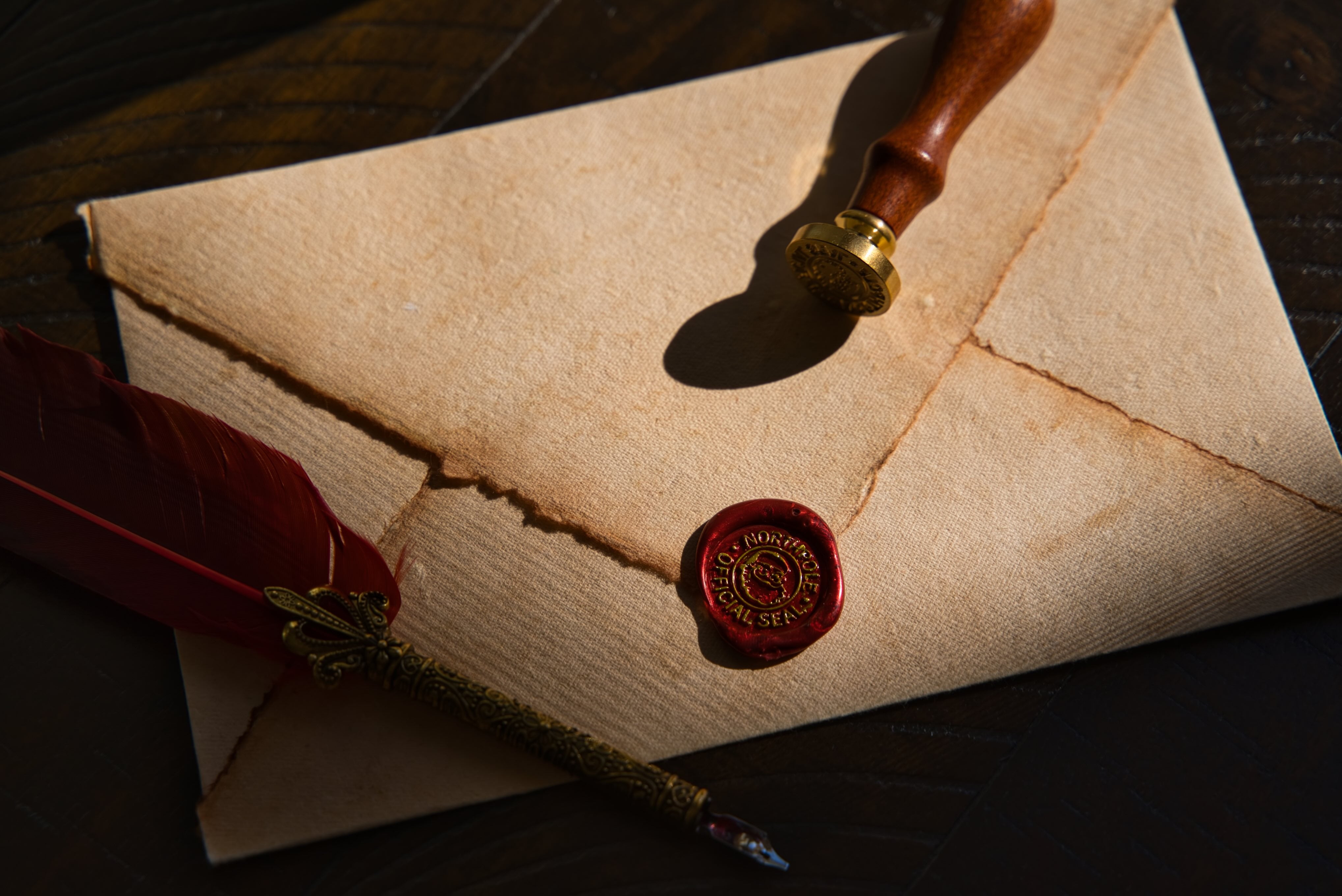 Vintage envelope with a red wax seal and a quill pen on a dark wooden surface
