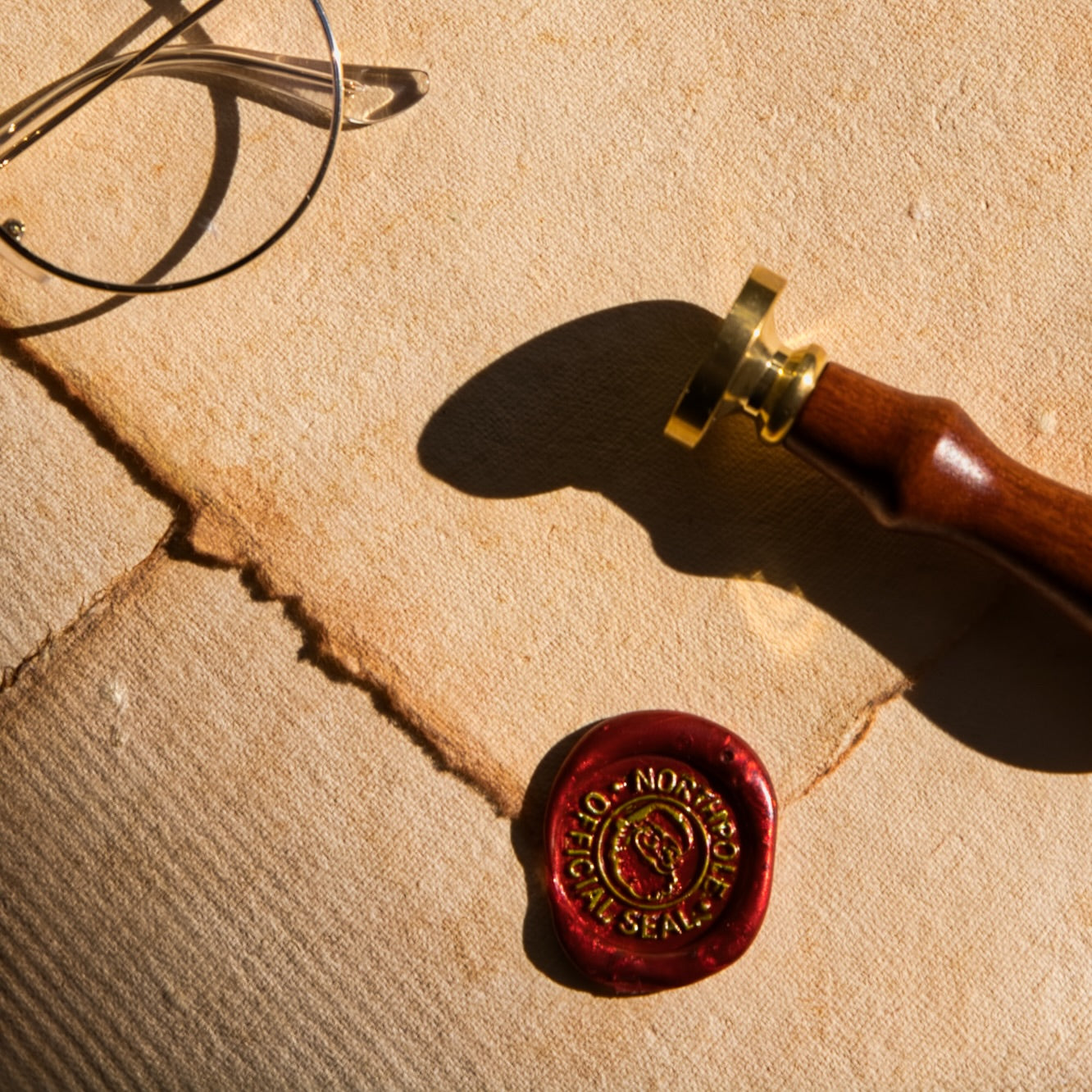 Red wax seal with a gold stamp on textured beige paper