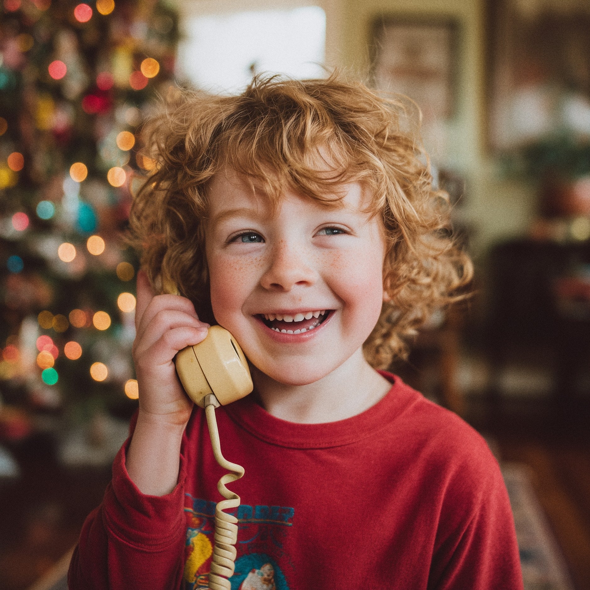 A joyful child talking with Santa Claus, with their family and a decorated Christmas tree in the background